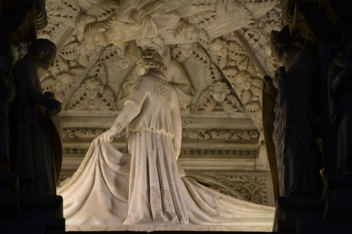 A large, intricately carved white marble shrine covered with sculpted figures and pinnacles, standing in the interior of a church.