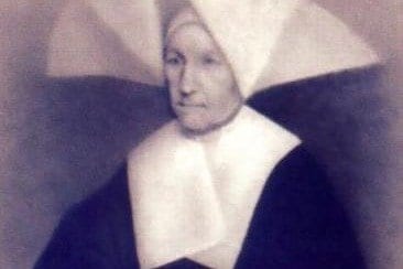 A sepia-toned photograph of an elderly nun in the wide winged cornette and black habit of the Daughters of Charity, seated and facing slightly to one side.