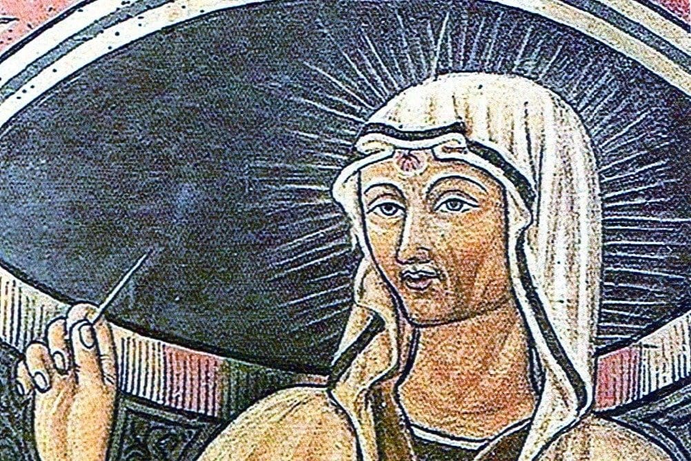 A painted portrait of a veiled woman with a halo of rays behind her head and a small mark on her forehead, holding a slender pointed object in one hand.