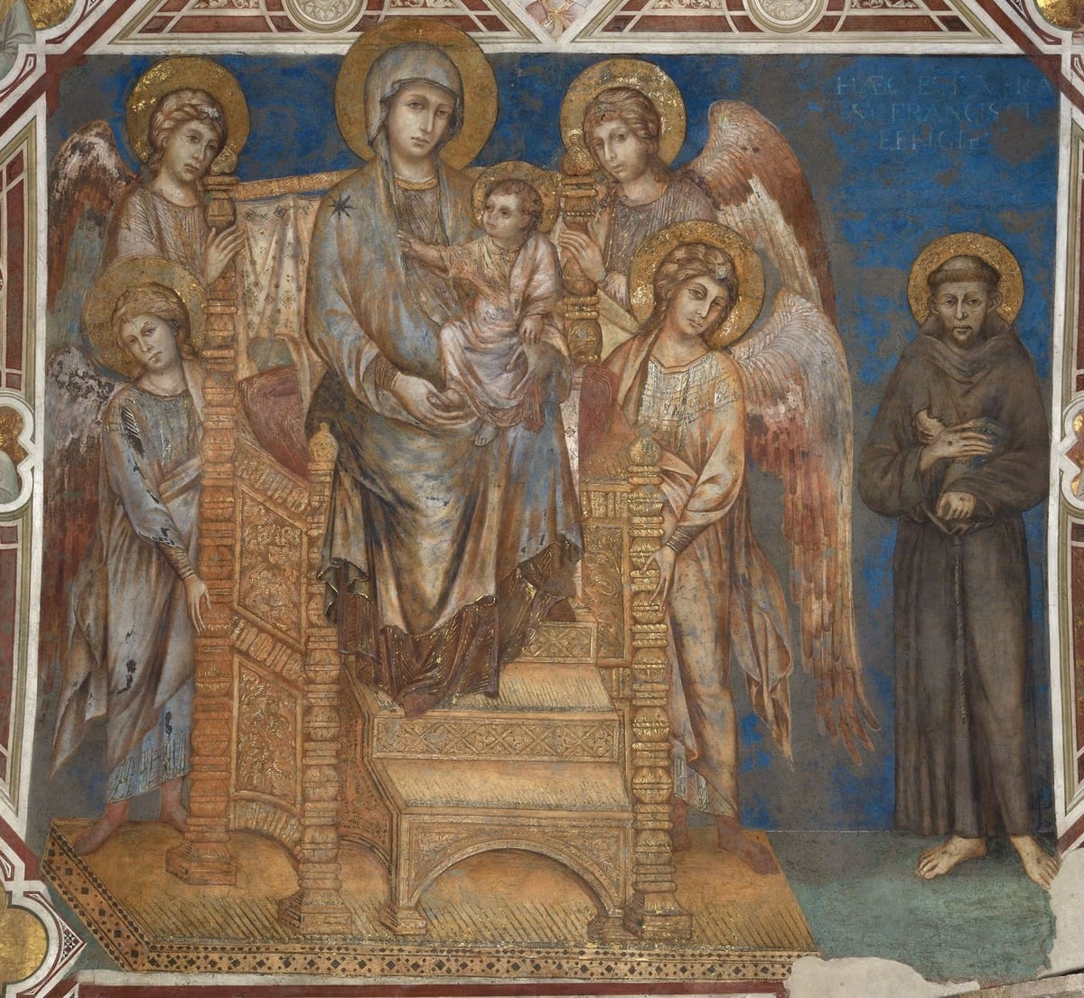 A medieval fresco of the Madonna enthroned with the Child in a gilded throne, flanked by four angels, with St. Francis standing barefoot in a brown habit at the right against a blue background.