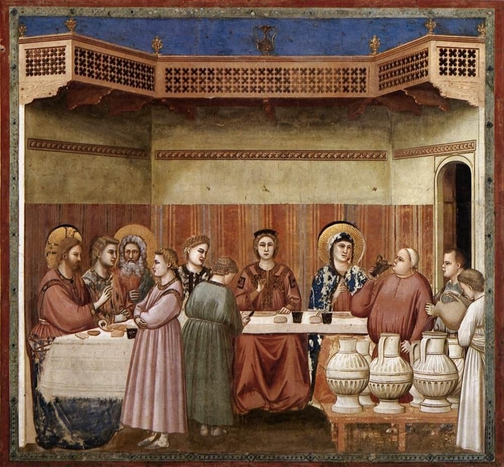 Giotto's fresco of the wedding at Cana: a long table in a loggia, with Jesus and the Blessed Virgin Mary, both haloed, seated at the left and right of the table, and large stone water jars in the foreground, with a servant pouring from one.