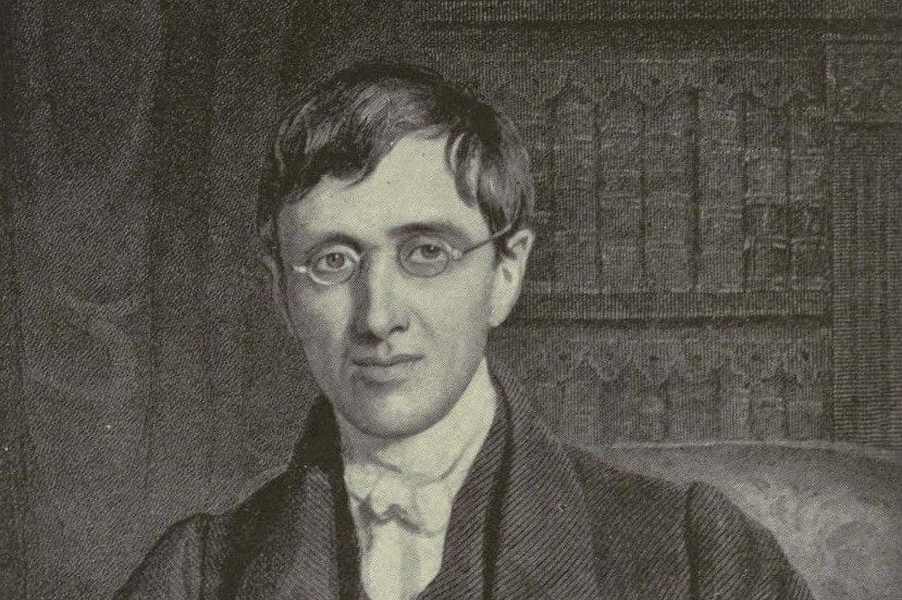 An engraved portrait of a young clergyman with wavy hair and round spectacles, seated in a chair before a carved Gothic bookcase, wearing a dark coat and waistcoat over a high white collar and cravat.