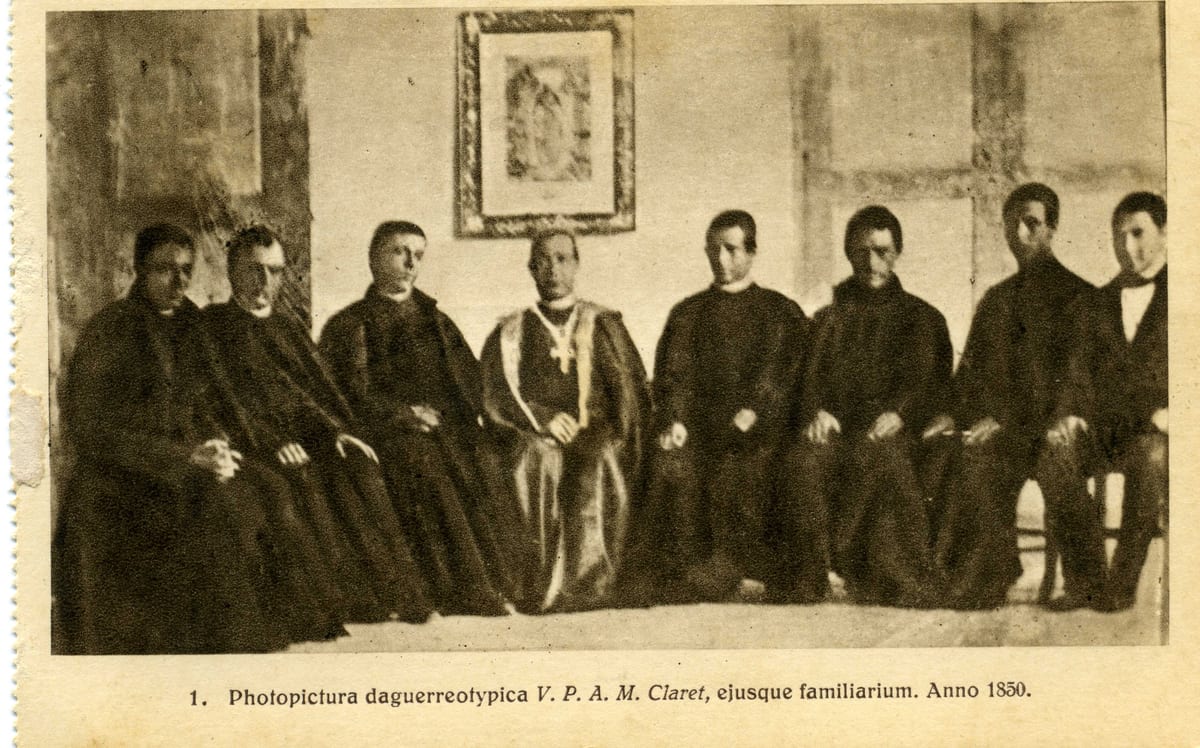 A daguerreotype of eight men seated in a row against a pale wall, the archbishop fourth from the left in a mozzetta with his pectoral cross.
