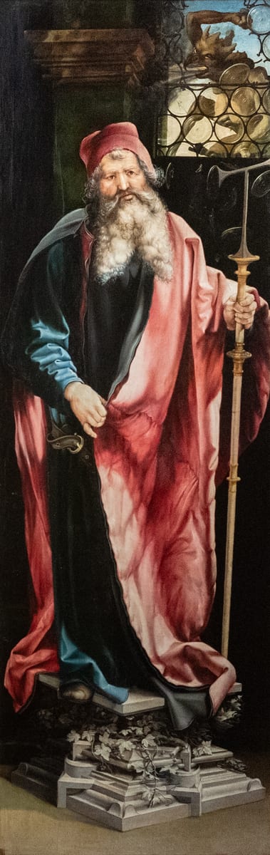 A painted panel shows St. Anthony as an abbot in a heavy dark mantle, with a tau-headed staff, a bell and a pig.