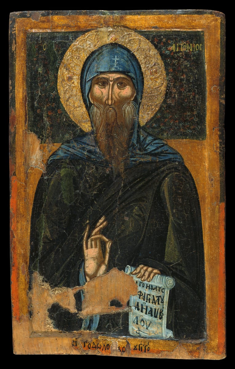 A painted icon shows St. Anthony standing full length as an old Egyptian monk, his head covered by a hood marked with crosses and his long white beard parted into two points.