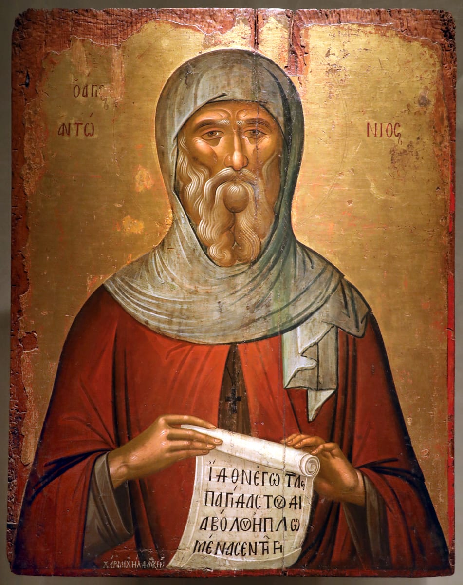A painted icon shows St. Anthony as an aged monk with a white forked beard and a hooded head, holding a scroll.