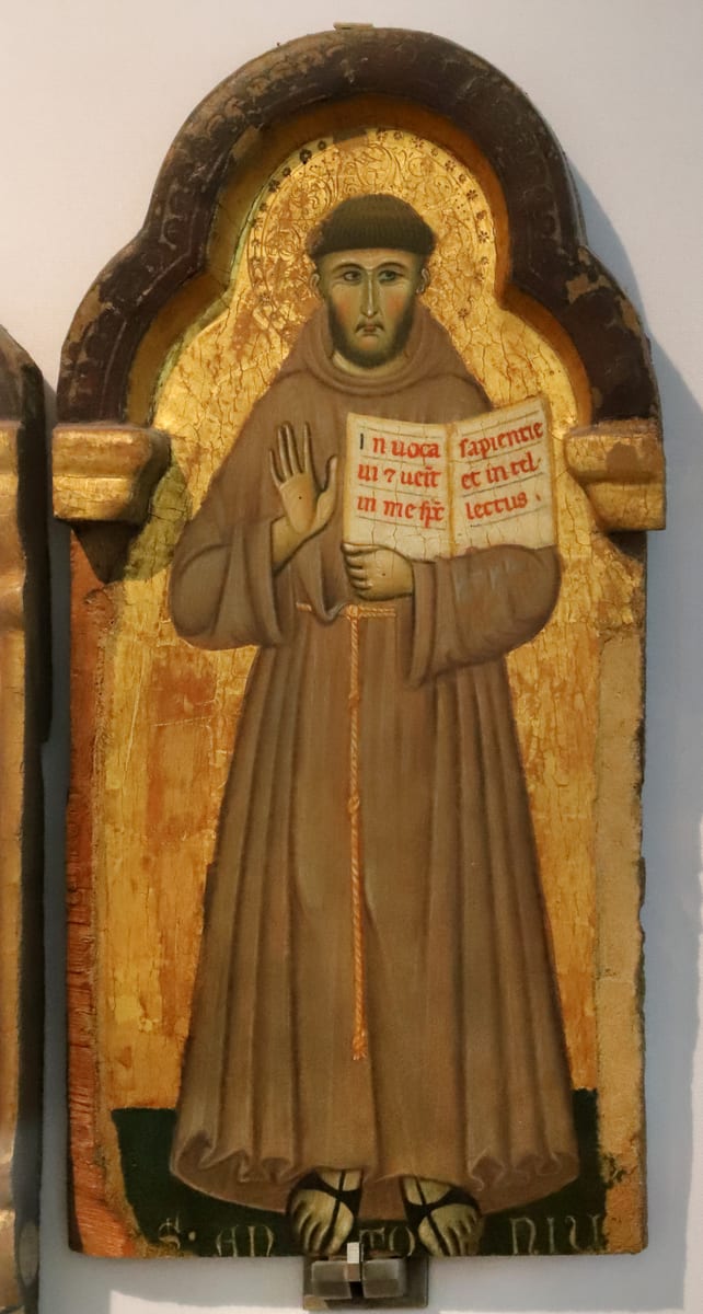 A gold-ground panel painting of a young tonsured friar in the Franciscan habit, standing frontally and carrying a book.