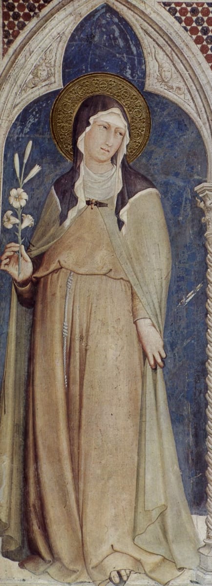 A fresco panel showing St. Clare of Assisi standing in a niche beneath a Gothic arch, wearing a brown habit with a white wimple and a gold halo, holding a stem of white lilies in her left hand.