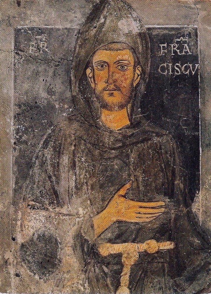 A half-length fresco portrait of a bearded friar in a hooded brown habit tied with a knotted cord, facing forward with one hand raised to his chest, against a dark background bearing the painted inscription of his name.
