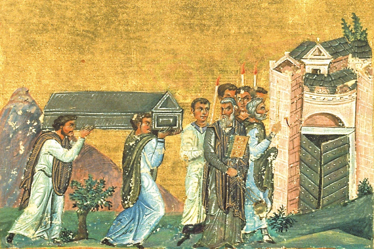 A Byzantine miniature shows two men carrying a reliquary chest on their shoulders toward a city gate, led by a bishop and clergy with candles.