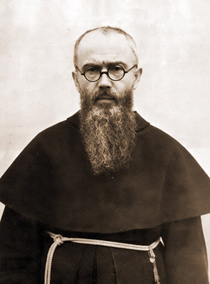A bald, bearded Franciscan friar in round wire-frame glasses and a dark habit tied with a knotted cord, photographed in half length against a plain backdrop, 1936.