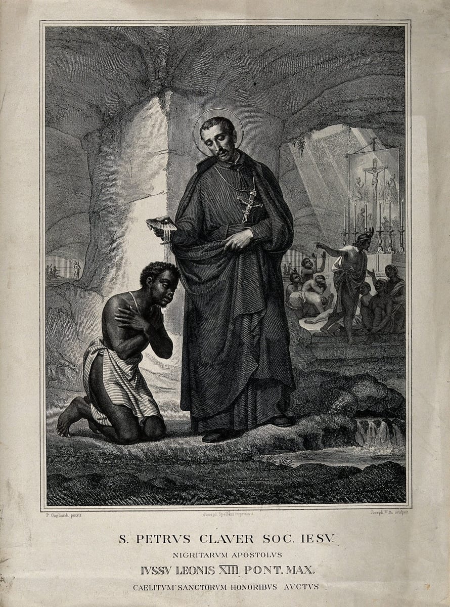 An engraving of St. Peter Claver, haloed and robed as a Jesuit priest with a crucifix at his breast, pouring water from a shell to baptize a kneeling African man with hands folded in prayer, set in a cave-like mission chapel where an altar with a crucifix and groups of enslaved Africans appear in the background.