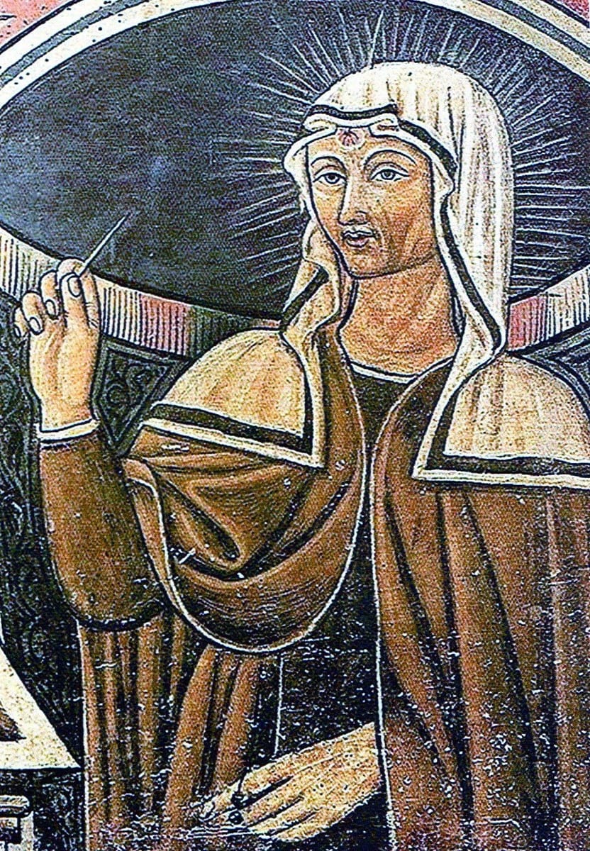 A nun in a dark habit and white veil, haloed, stands holding a small scourge in one raised hand and a book in the other, a red mark visible on her forehead beneath the veil's edge.