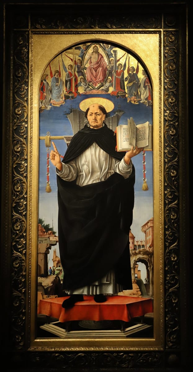 A tonsured Dominican friar in black cappa over white habit stands haloed above a red-draped altar, right hand raised with a finger pointing upward, left hand holding an open book, with a rosary hanging from a staff beside him and Christ enthroned among angels in the gold sky above, ruined classical architecture and a walled town in the background.